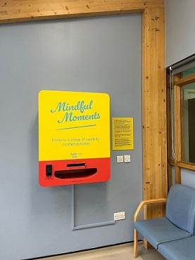 Mindful Moments vending machine on wall with a gap where the activity packs are dispensed.