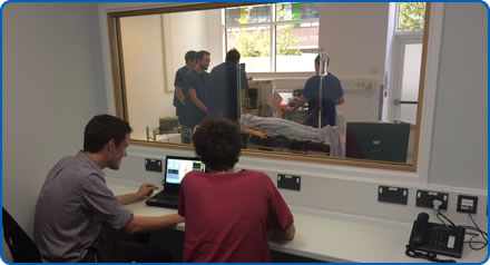 Trainers watch clinicians carrying out a scenario using a manikin in the Sim Space at Southmead Hospital