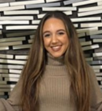 Woman standing against geometric background wearing beige jumper