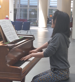 Alex a volunteer playing the piano in the atrium of the Brunel building.