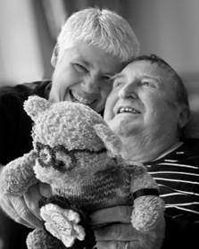 Amanda and David Amanda with her husband David, both smiling and holding a teddy