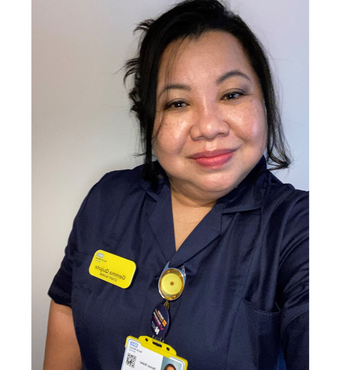 Gemma Quijote smiling at the camera wearing a navy nursing uniform