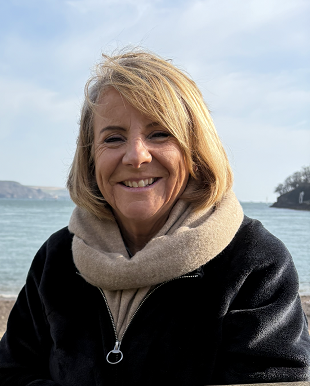 Women and Children's Health Divisional Director of Nursing and Midwifery, Julie Northrop A woman smiles. She is wearing a coat and scarf, the sea can be glimpsed behind her