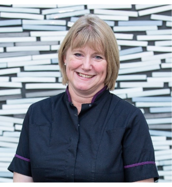 Juliette Hughes smiling at the camera wearing a black tunic