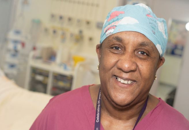 NBT Theatre Coordinator Marcia Dawkins in scrubs and protective headwear.