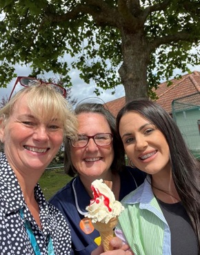 Three women grouped together, smiling. One in navy blue midwife uniform holds an ice-cream