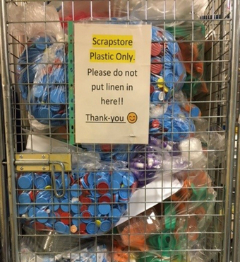 Plastic waste in a metal cage with the sign 'Scrapstore Plastic Only -Please do not put linen in here!'