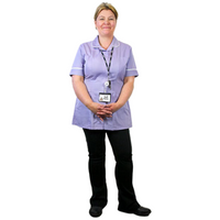 A nurse standing up wearing a purple tunic smiling at the camera