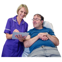 Nurse in a purple uniform completing a paper checklist with a patient who is lying on a bed