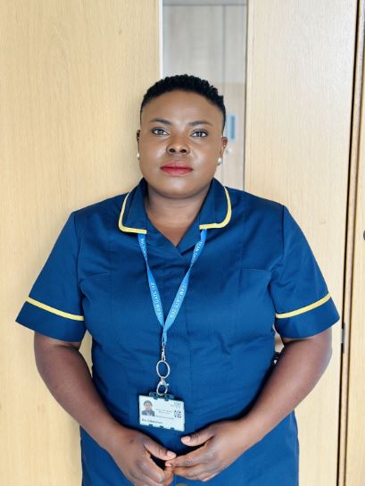 Olajumoke Olagookun, a Band 7 Senior Chief Nursing Officer Fellow at NBT, standing in uniform in front of a wooden door