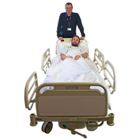 Patient in a hospital bed being pushed by a porter in navy clothing