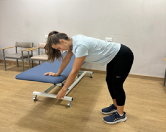 woman bent hips at 90 degree angle, one am leaning on a couch, one arm swinging at side