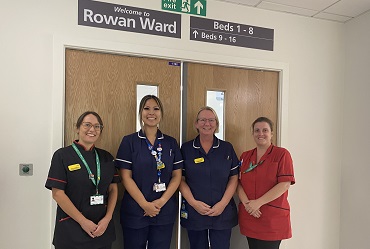 Four nurses in uniform stand outside a door, the sign above it reads Rowan Ward