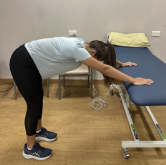 woman bent over at 90 degree angle with arms stretched out and both hands resting on couch