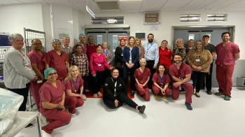 The Gynaecology Team at North Bristol NHS Trust stands in front of two sets of double doors outside an operating theatre.