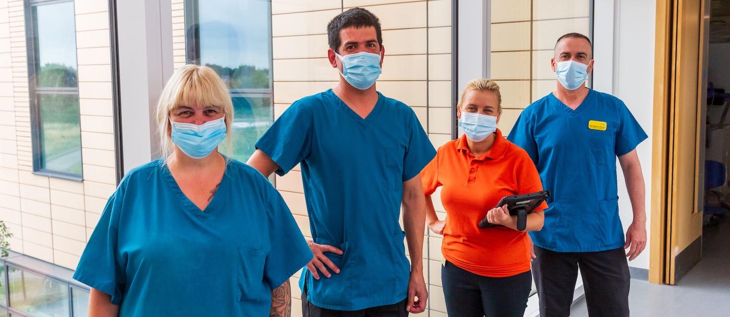 Domestic Team lined up in corridor wearing masks