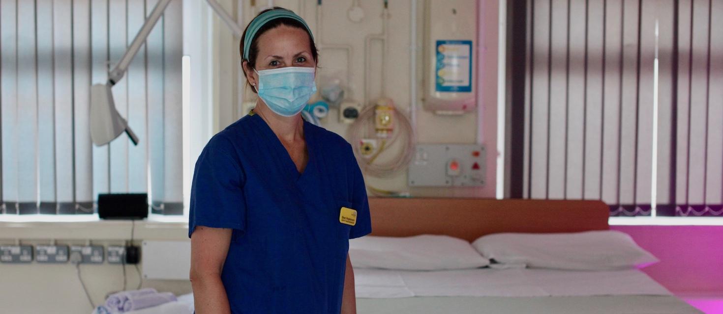 Midwife standing a room with a bed