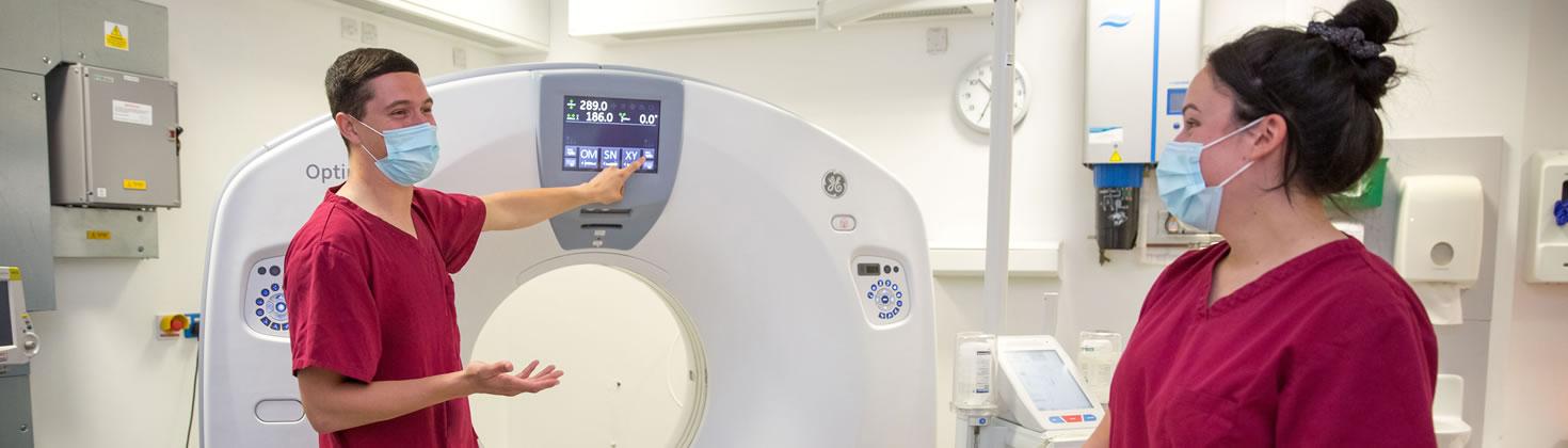 Two members of staff in masks at a CT scan