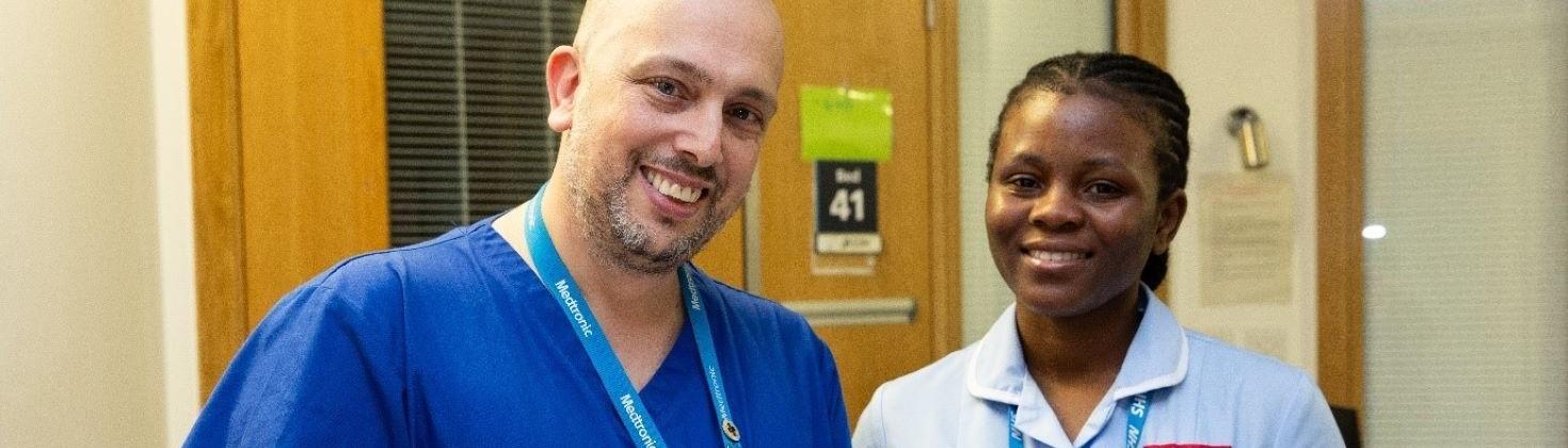 Man wearing medical scrubs smiling next to woman in nurses uniform smiling