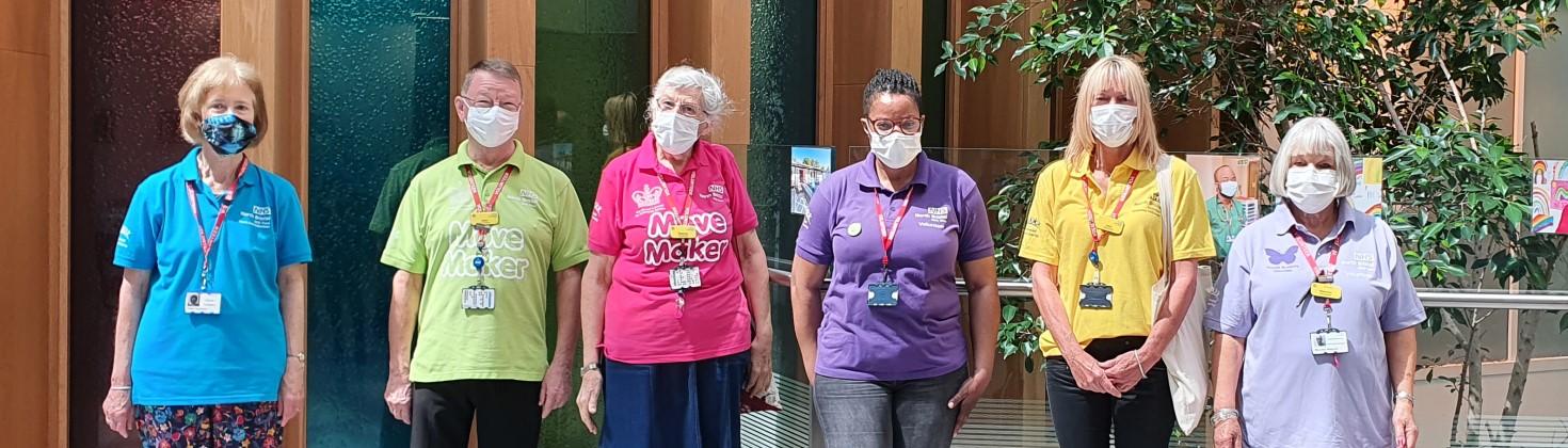 Volunteers from around the Trust wearing different colour polo shirts pose wearing surgical masks