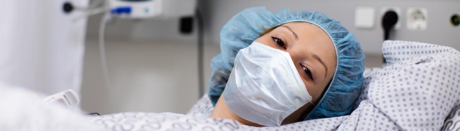 Patient wearing a face mask, lying in hospital bed