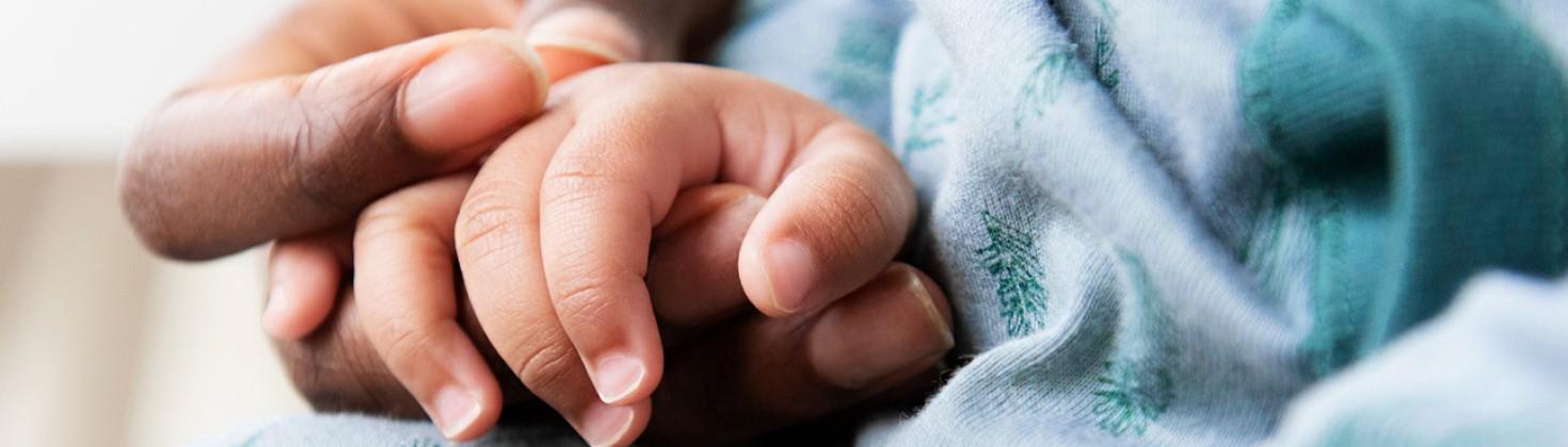 Newborn holding hands with its mother