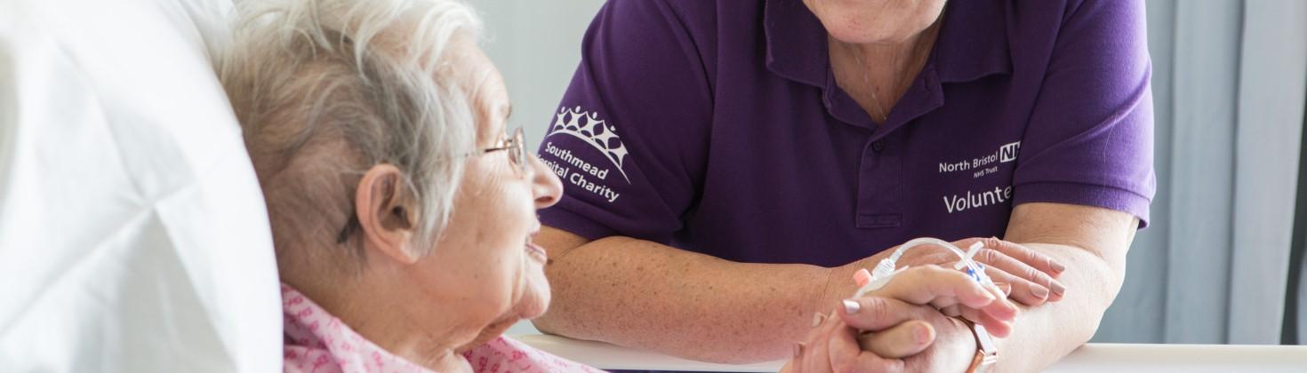 volunteer wearing purple polo shirt chatting with a patient 