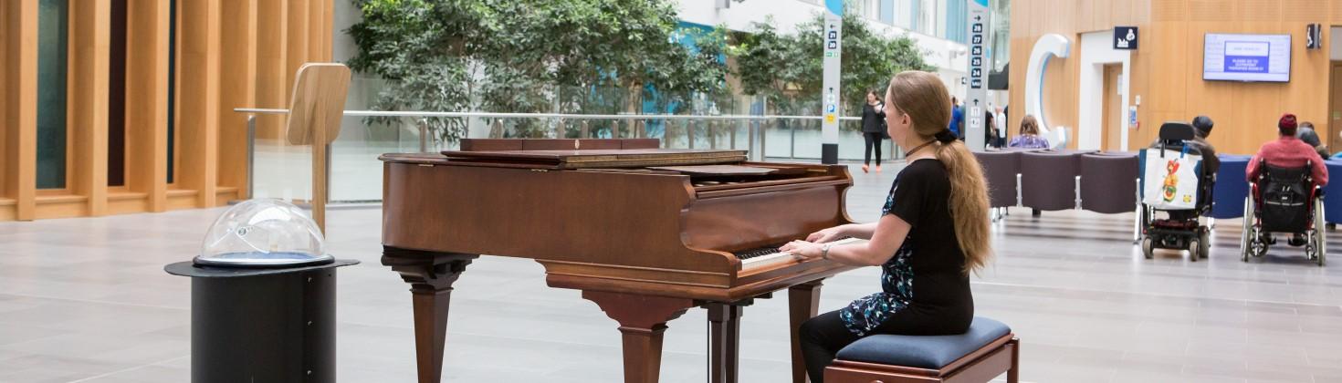 volunteer piano player sitting at piano within the building atrium