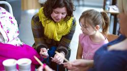 Artist Ali Brown teaches a young visitor a new skill as part of Knit With Me.