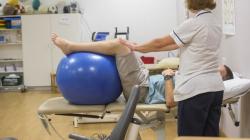 Physiotherapy patient with legs on a blue gym ball