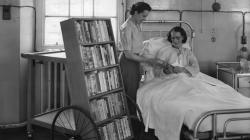 Black and white photo of A patient choosing books from the Southmead mobile library.