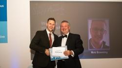 Man in suit receives certificate from man in tuxedo