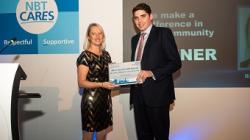 Woman in a sparkly dress is handed a certificate by a man in a suit