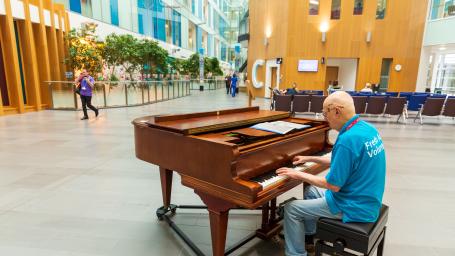 A volunteer musician plays the piano in the Brunel atrium.