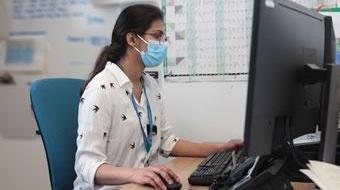 Information Governance - lady wearing face mask sitting at computer