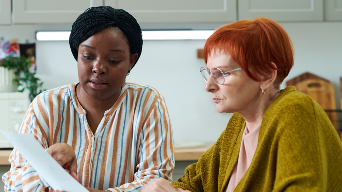 Two women sat at a table holding a sheet of paper