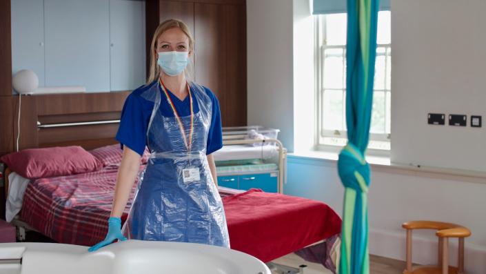 Midwife standing a room with a bed