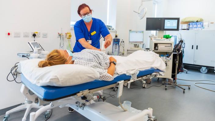 Obstetric Sonographer with lying down patient using device on stomach