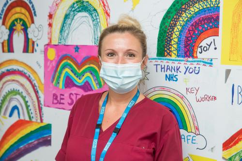 North Bristol NHS Trust staff member standing in front of a display of rainbow drawings