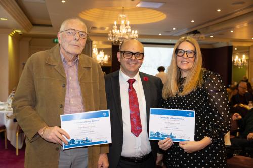 Two men and women stood together, two holding certificates