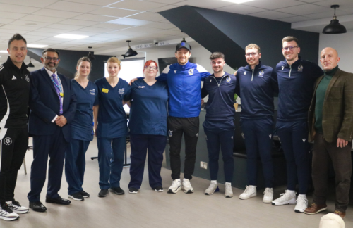 Members of Bristol Rovers, Bristol Rovers Community Trust, North Bristol NHS colleagues and UHBW colleagues stood in a semi circle at the CPR Session
