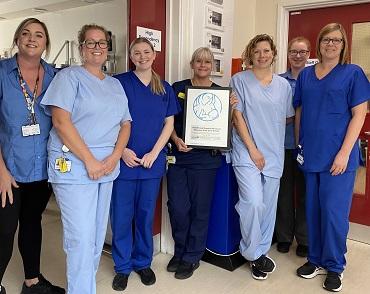 Group of Healthcare staff in blue scrubs holding a certificate