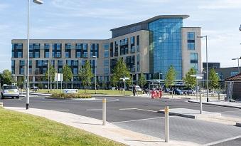 A large building with grass in front and a car park sign in the forefront