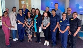 A group of male and female nurses, some in uniform, some not, smiling and celebrating