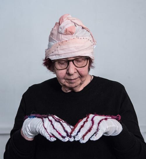 Women looking down with gloves with red string and a pink and white hat on 