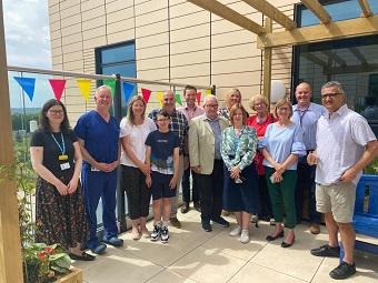 A group of Intensive Care Unit staff, former patients and senior staff gathered in the terrace garden with colourful bunting