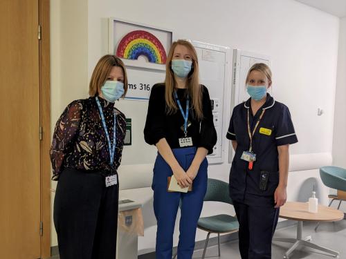 Chief Executive, Maria Kane, giving thank you cards to two staff members.