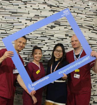 NBT apprentices posing in blue selfie frame with the text '#ApprenticeshipsatNBT'