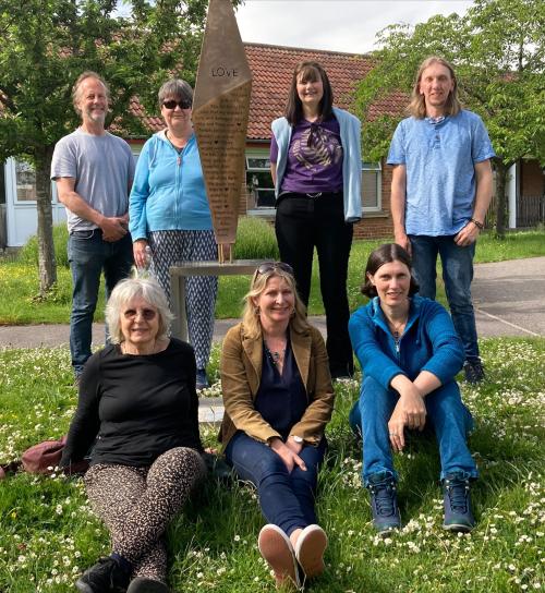 A photo of 7 people next to a bronze sculpture 