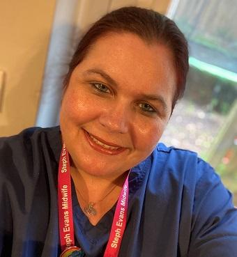 Bereavement Midwife Steph, in blue scrubs uniform, looking at the camera and smiling